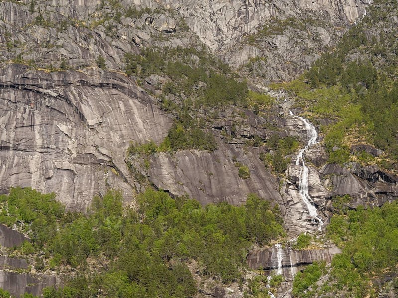 A high waterfall cascades down between steep rocks and wooded cliffs, Eidfjörd, Norway, Europe