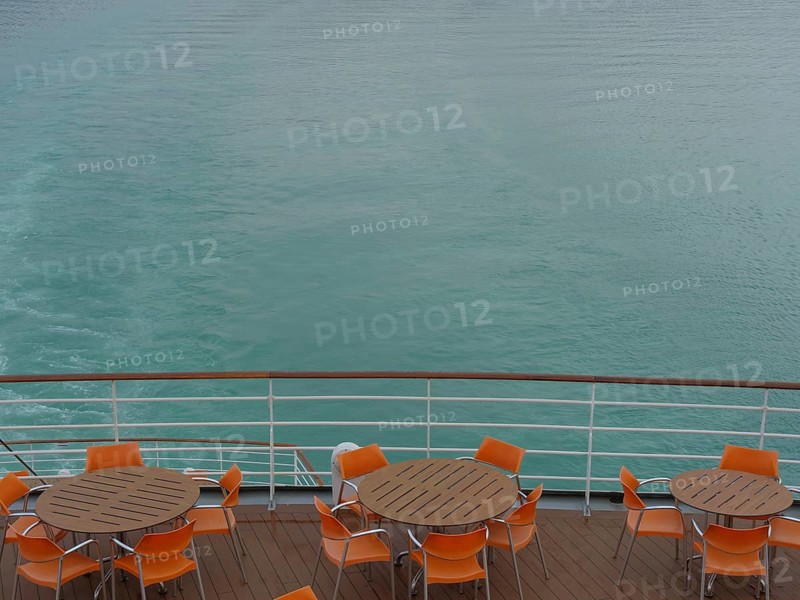 Deck of a ship with tables and chairs in orange, calm water in the background, Eidfjord, Norway, Europe