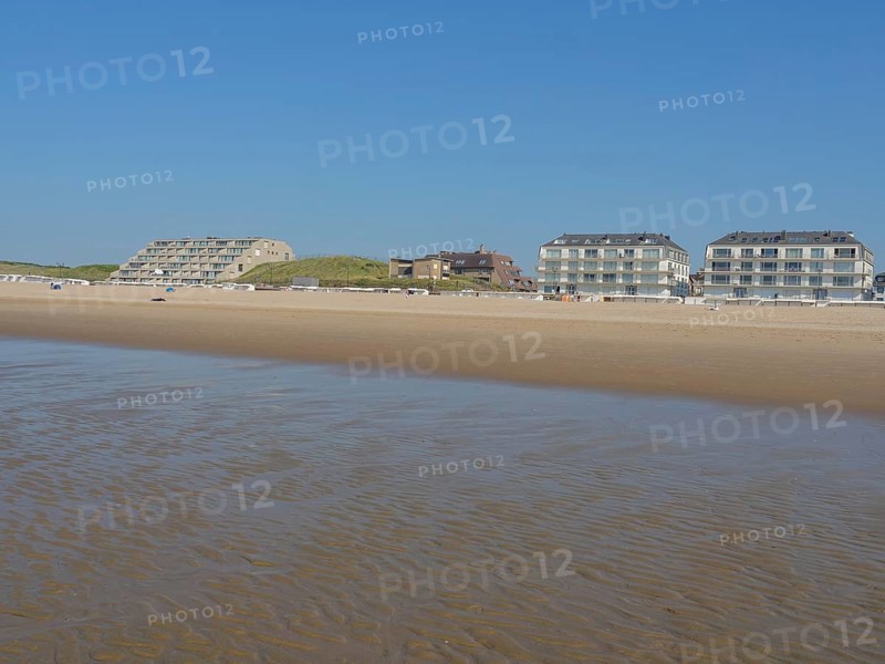 Building on a vast sandy beach with calm sea and blue sky in the background, de haan, belgium