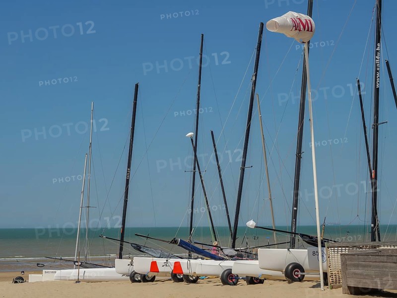 Several sailing boats on the beach, the sea and a clear blue sky in the background, de haan, belgium