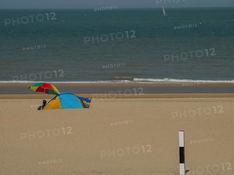 Colourful tent and parasol on a sandy beach, with calm sea in the background on a sunny day, de haan, belgium