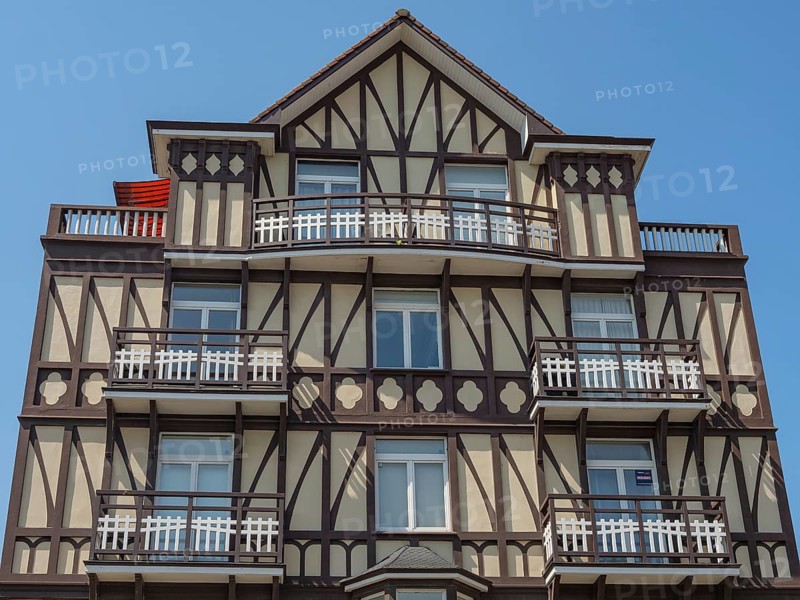 Facade of a multi-storey half-timbered house with balconies on a sunny day, de haan, belgium