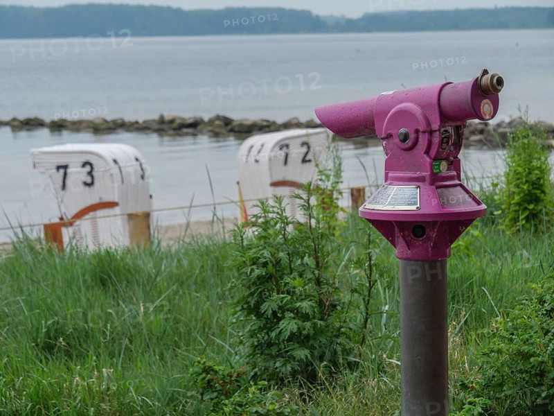Purple binoculars with a view of numbered beach chairs and the calm sea, Eckernförde, SChleswig-Holstein, Germany, Europe