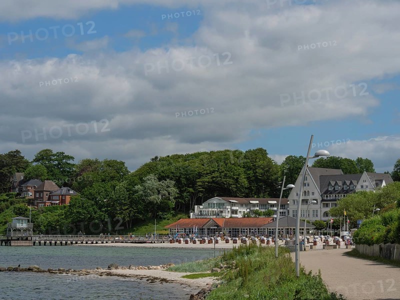 A coastal landscape with a promenade, small houses and green areas under a slightly cloudy sky, Glücksburg, Schleswig-Holstein, Germany, Europe