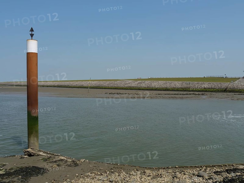 A coastal scene with a post in the water and a rocky shore under a clear sky, Hallig Hooge, schleswig-holstein, germany