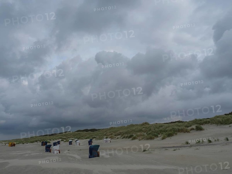 Empty beach with beach chairs, large dunes and dark grey clouds in the sky, juist, east frisia, Germany, Europe