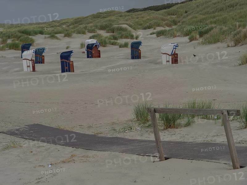 Beach with wooden path, several beach chairs and dunes, sand and cloudy sky, juist, east frisia, germany