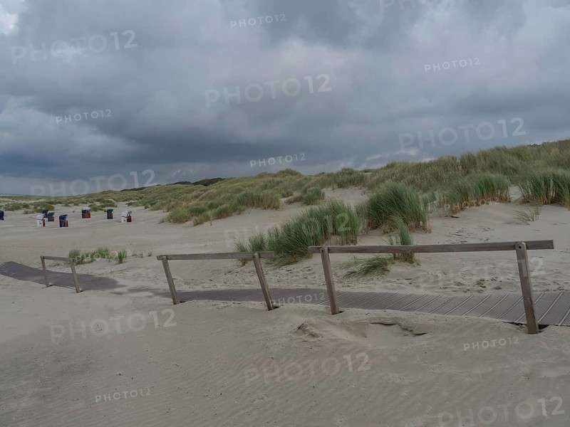Beach shot with wooden path, dunes, sand and cloudy sky, scattered beach chairs in the background, Juist, East Frisia, Germany, Europe