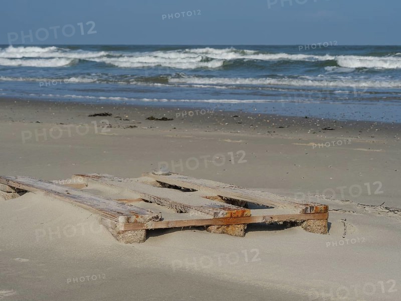 Old wooden pallets lying on the beach, with waves of the sea in the background, juist, east frisia, germany