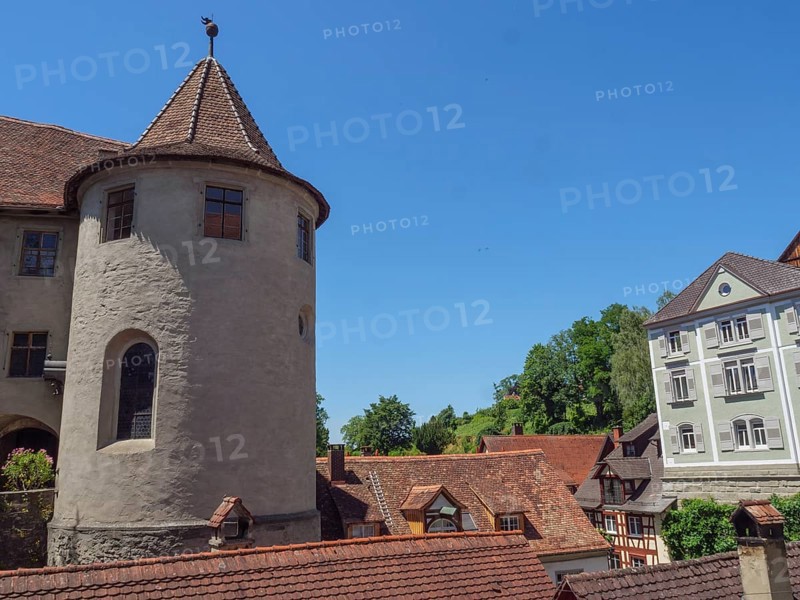 A castle with a round tower and surrounding roofs of historic buildings under a clear blue sky, Meersburg, Germany, Europe