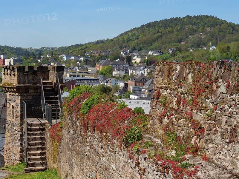 Historic tower and castle wall overlooking a green, hilly urban landscape on a sunny day, Saarburg, Germany, Europe