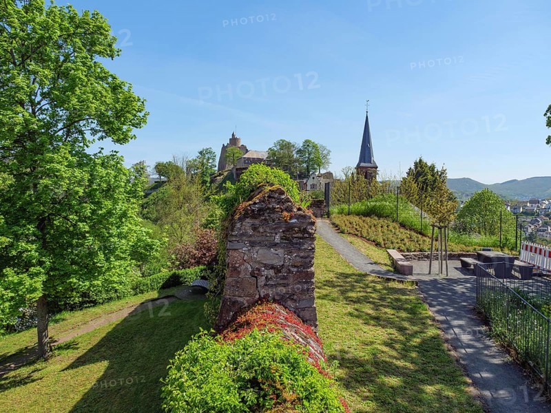 Garden with ruins and a church tower in the background, surrounded by trees on a sunny spring day, Saarburg, Germany, Europe