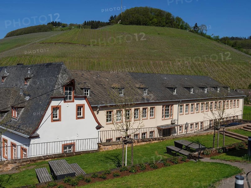 Large building in the middle of a rural, hilly landscape with meadows and trees in sunny weather, Saarburg, Germany, Europe