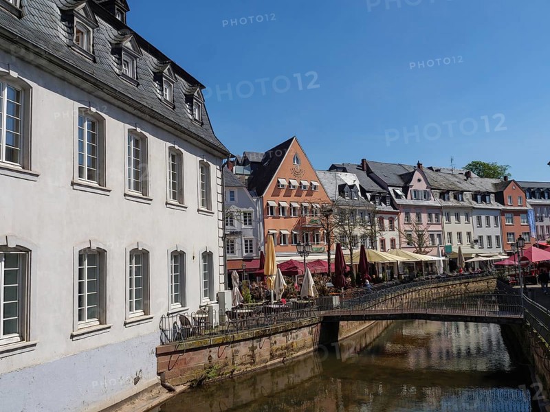 Scenic view of an urban scene with river, buildings, a bridge and sunshades along a canal, Saarburg, Germany, Europe