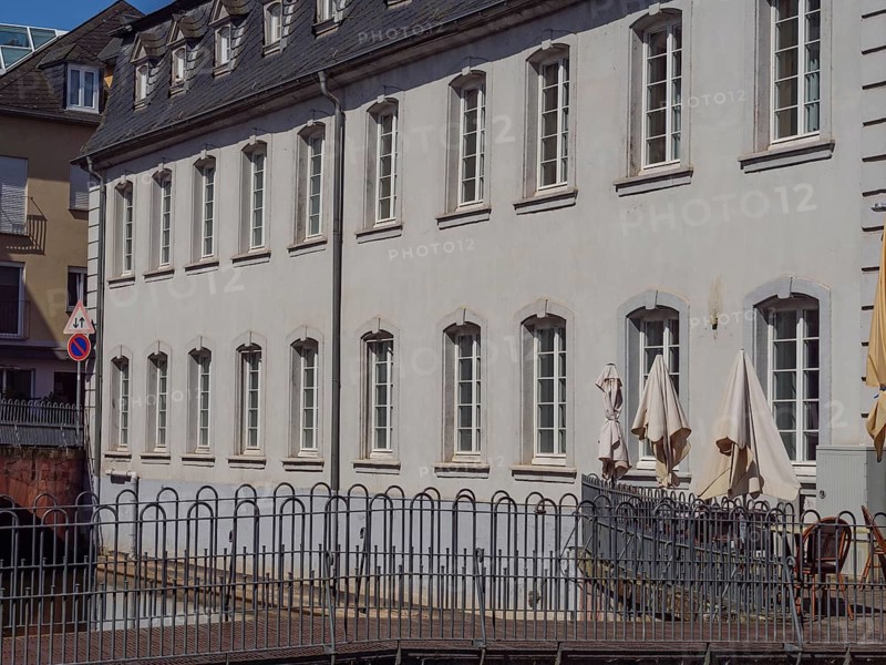 An urban sight with white buildings, lots of windows, parasols and a low barrier, Saarburg, Germany, Europe
