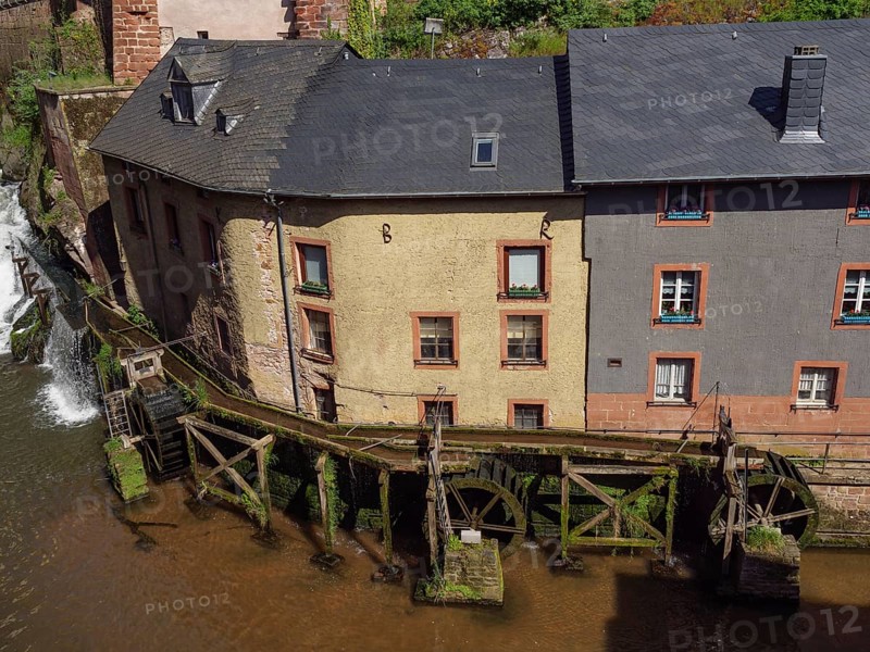 Close-up of a watermill with old buildings on the river, wooden mechanism visible, Saarburg, Germany, Europe