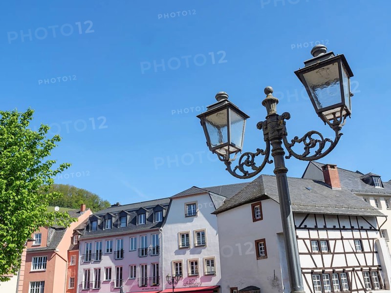 View of a historic street with half-timbered houses and a street lamp under a clear blue sky, Saarburg, Germany, Europe