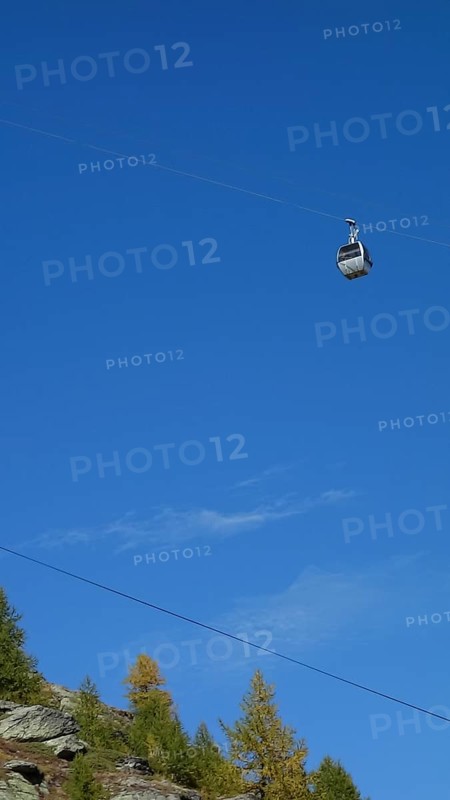 A cable car in front of a bright blue sky over an autumn-coloured mountain, Saas Fee, Switzerland, Europe