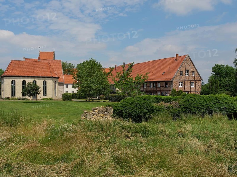 View of an estate with a church, tiled roofs, surrounded by lawns and trees under a blue sky, Steinfurt, North Rhine-Westphalia, Germany, Europe