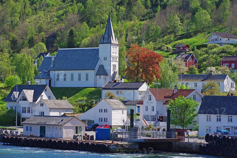 Village with church on a green hill, surrounded by wooden houses and a ferry pier, Utne, Hardanger, Hardangerfjord, Norway, Europe