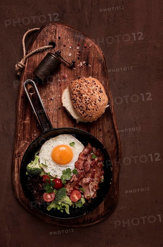 Spiegelei, mit Speck und Gemüse, in einer gusseisernen Pfanne, Ansicht von oben, hausgemachtes Frühstück
