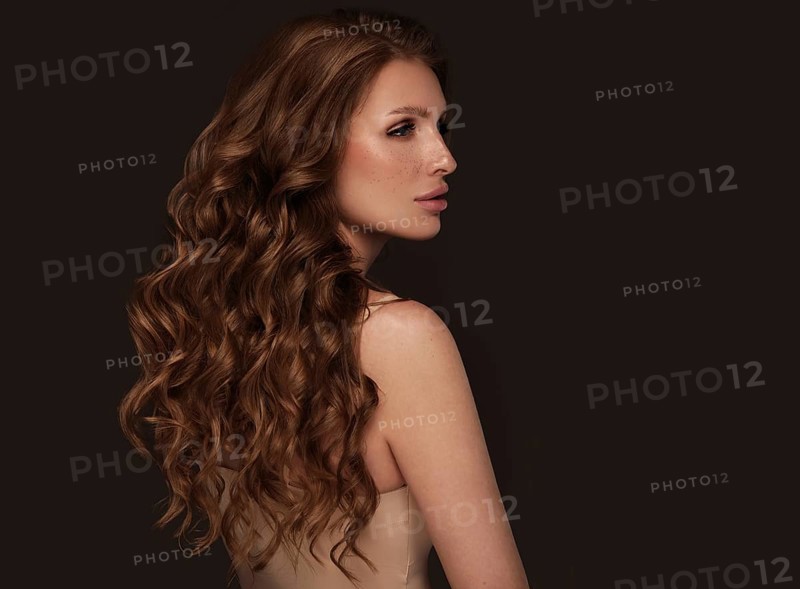 Beautiful brown-haired girl with a perfectly curls hair, and classic make-up. Beauty face and hair. Picture taken in the studio