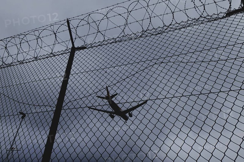An aircraft looms over a barbed wire fence, taken at Berlin Brandenburg Airport 'Willy Brandt'Äô (BER) in Schönefeld, 08/08/2024