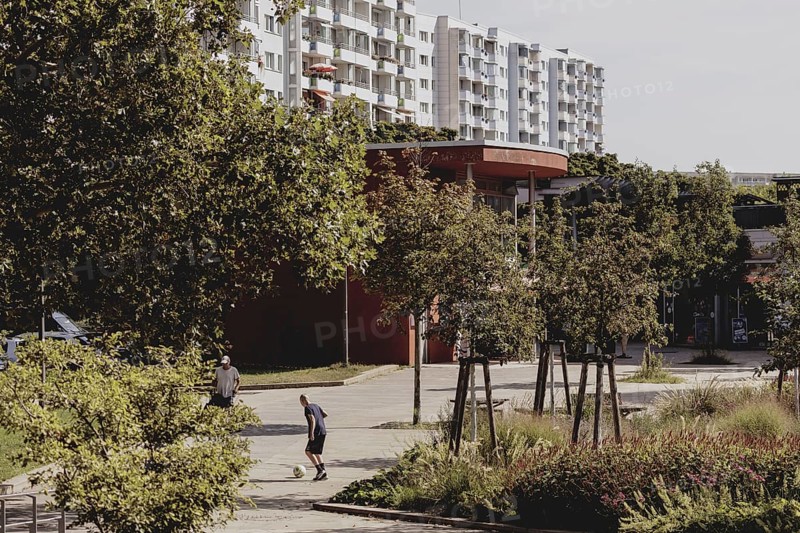 A boy with a football stands out in a green area between blocks of flats in Marzahn, taken in Berlin, 07/08/2024
