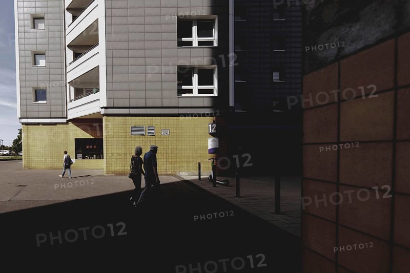 Two elderly people are silhouetted in front of a block of flats in Marzahn, taken in Berlin, 07/08/2024