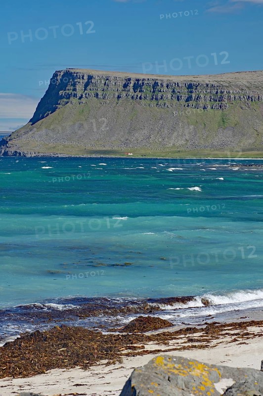 A rocky coastline with sharp-edged cliffs jutting out into the blue sea, Latrabjarg, Vestfirdir Peninsula, Iceland, Europe