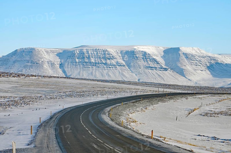 Snowy road leads to a snow-covered mountain range under a clear blue sky, Ring Road, North Iceland, Iceland, Europe