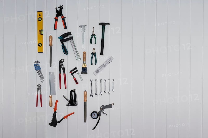 Tools on the wall, file, rasp, stapler, blind rivet pliers, spirit level, hammer, metre rule, open-ended spanner, pliers, saw, Allen key, screw clamps, punch pliers, calliper gauge, with text space