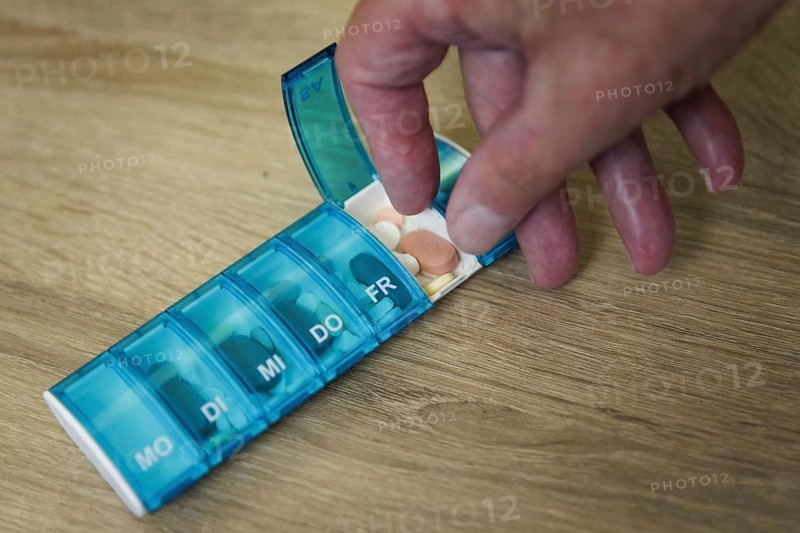 An elderly man takes pills from a pill box. Berlin, 05.08.2024