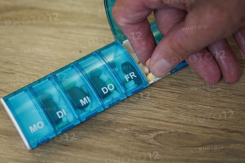 An elderly man takes pills from a pill box. Berlin, 05.08.2024