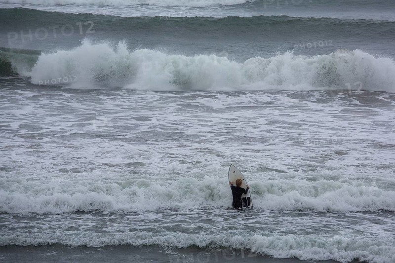 A surfer enters the water on an ideal day for surfing along the Wild Atlantic Way. Strandhill, Sligo, Ireland, Europe