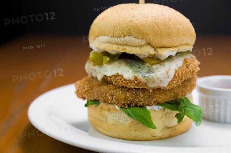 Close-up of homemade tasty chicken burger on wooden table and black background