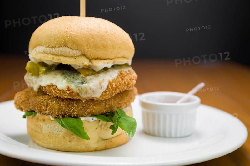 Close-up of homemade tasty chicken burger on wooden table and black background