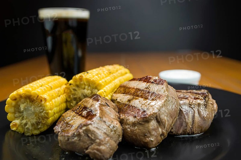 Delicious filet mignon close-up with roasted corn and glass of beer