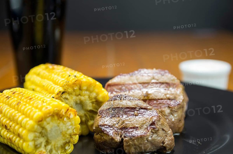 Delicious filet mignon close-up with roasted corn and glass of beer