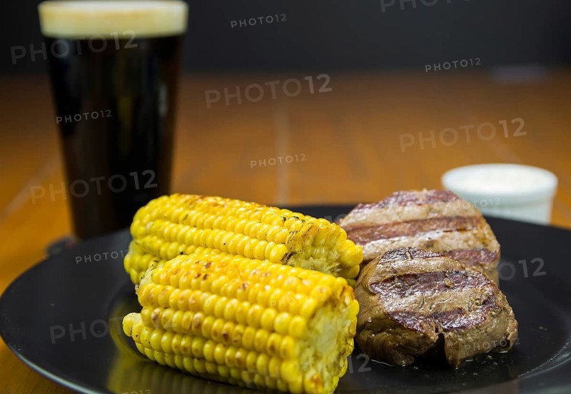Delicious filet mignon close-up with roasted corn and glass of beer