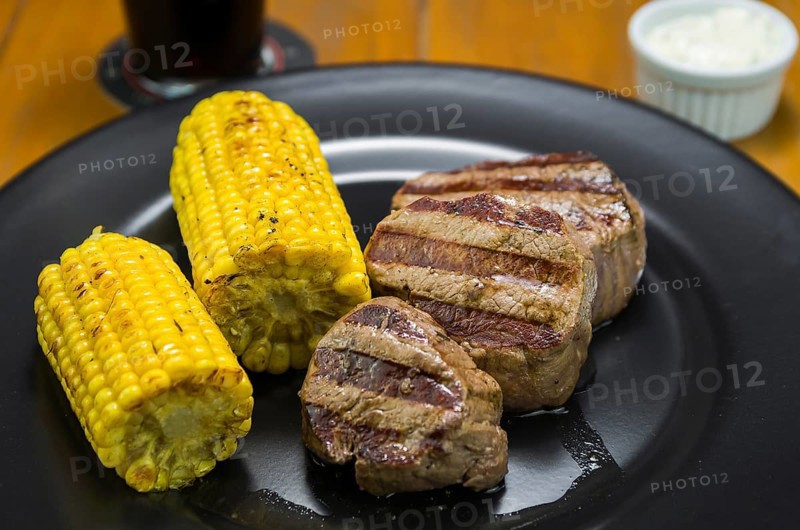 Delicious filet mignon close-up with roasted corn and glass of beer
