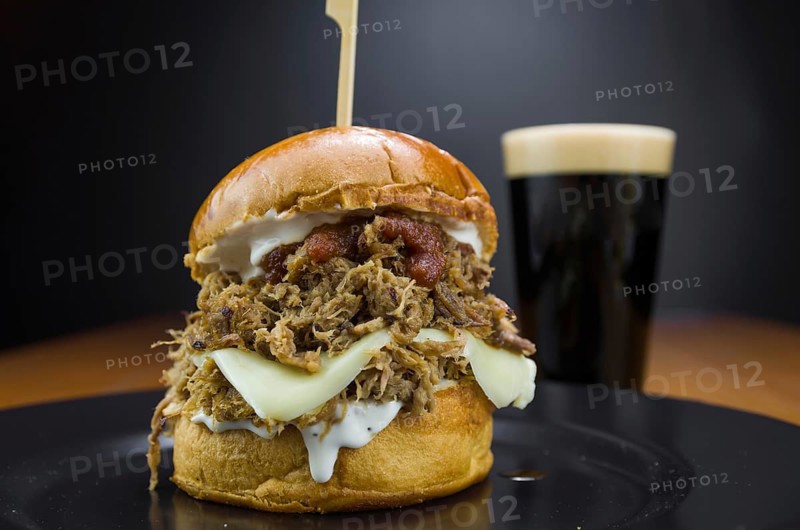 Close-up of tasty homemade pulled pork burger on wooden table and black background