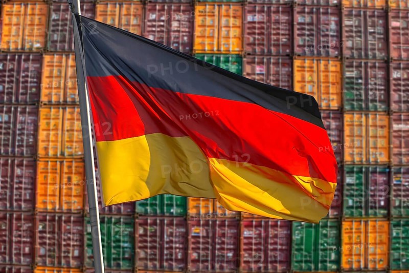Symbolic image of the German economy: German flag in front of a large stack of shipping containers (Composing)