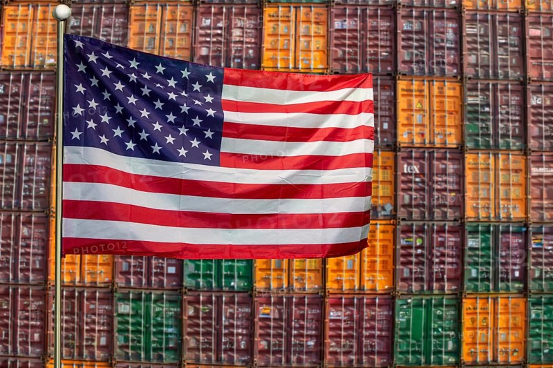 Symbolic image of the US economy: USA flag in front of a large stack of shipping containers (Composing)