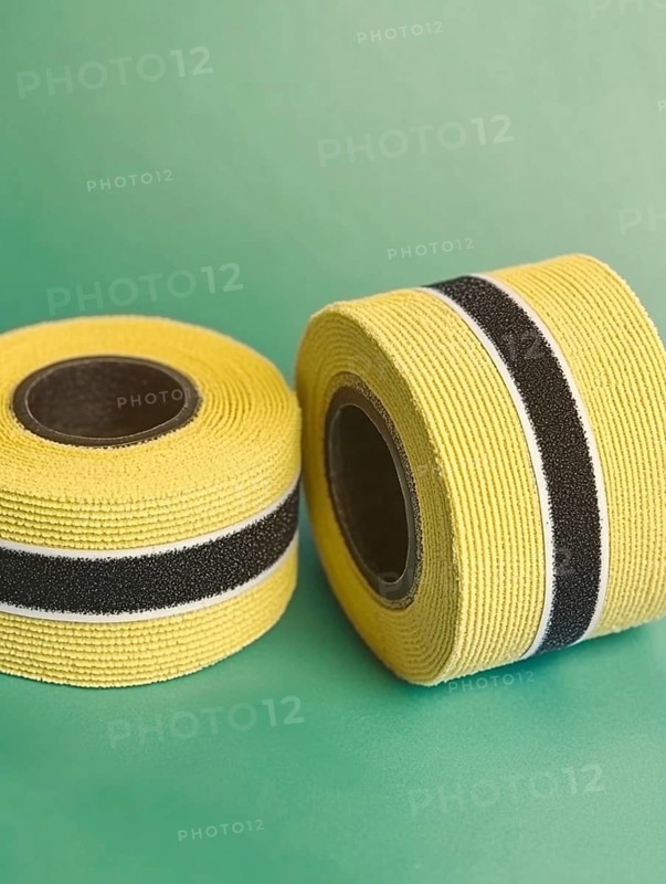 Yellow ribbon rolls with black stripes on a green background, AI generated