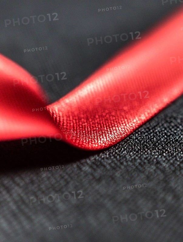 Close-up of a red satin ribbon placed on a black textured background, AI generated