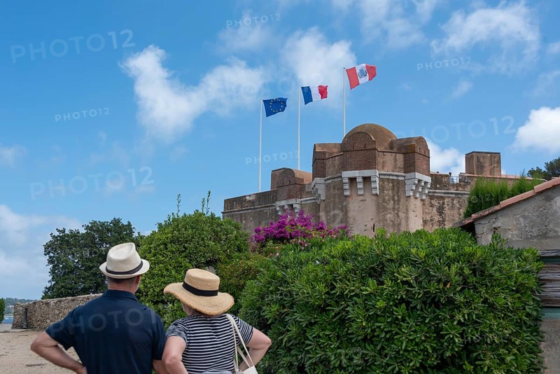Two tourists stand in front of the citadel of Saint-Tropez, built in 1602 as a defence against the Ottoman Empire, behind it a bay with a yacht, Saint Tropez, Provence-Alpes-Côte d'Azur, France, Europe