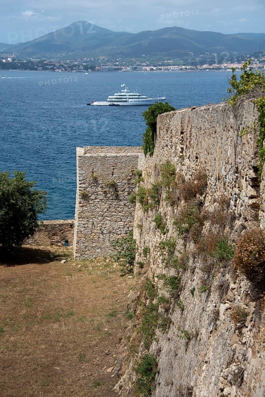 Historic walls of the citadel of Saint-Tropez, built in 1602 for defence against the Ottoman Empire, bay with yacht behind, Saint Tropez, Provence-Alpes-Côte d'Azur, France, Europe