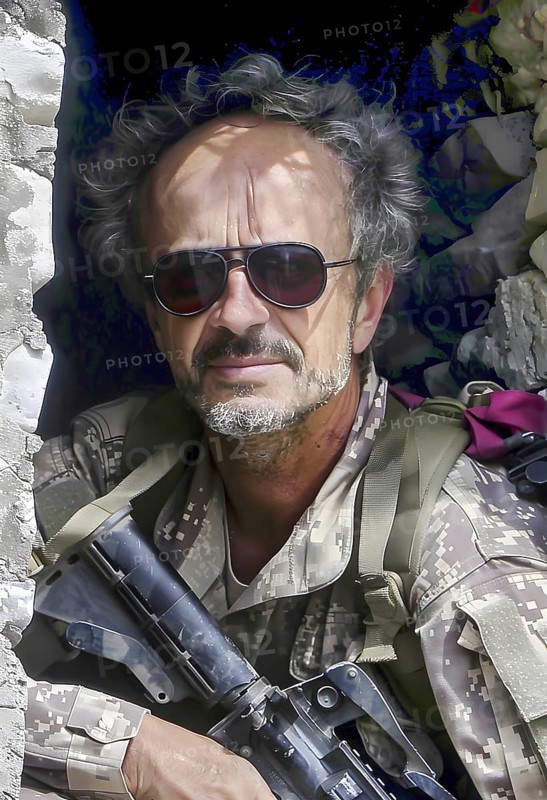A soldier in uniform with sunglasses and an assault rifle looks at his surroundings from a shot-up house wall, AI generated, AI generated