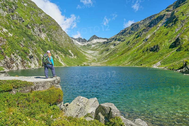 Hiker looking at the Dorfer See in the background the Kalser Tauern, mountain lake, blue sky, Dorfertal, Hohe Tauern National Park, Kals am Grossglockner, East Tyrol